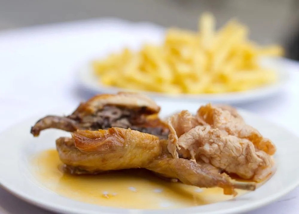 Codorniz com molho picante e bifana, batatas fritas atrás