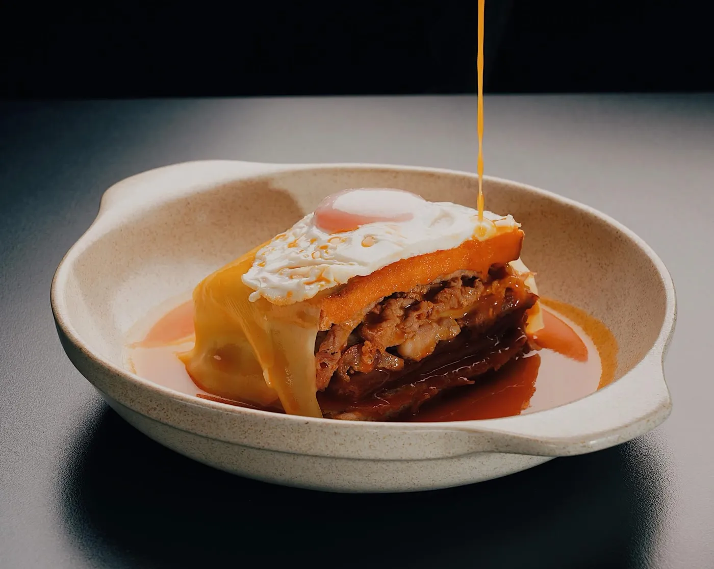 Francesinha com ovo estrelado, o molho a escorrer
