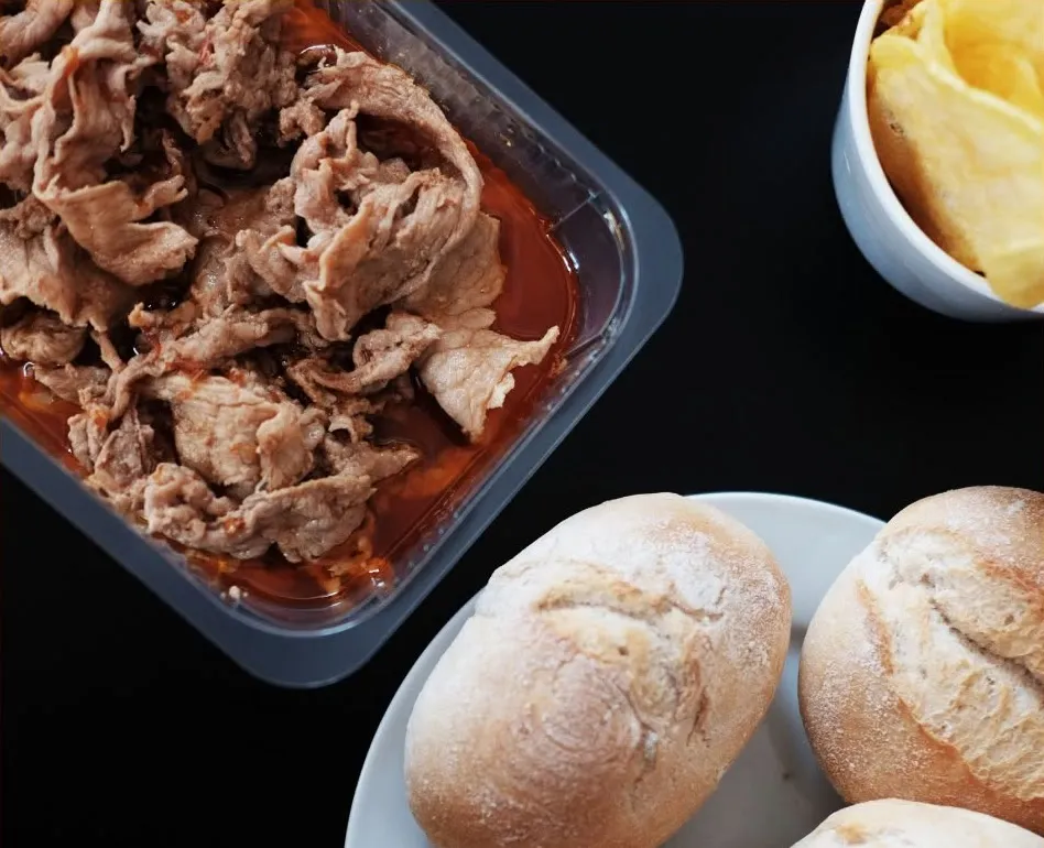 Bifanas sem pão numa embalagem, com pães e batatas fritas