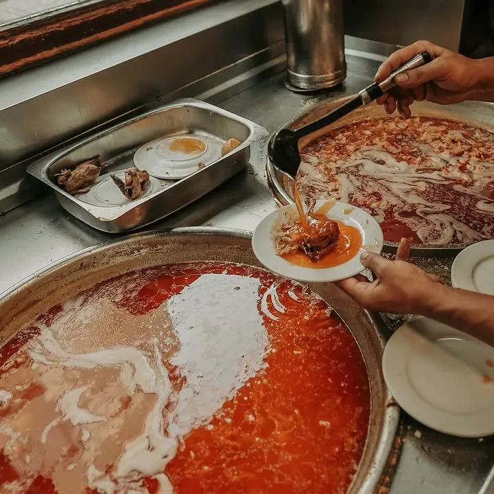 A concha deita o molho picante sobre uma bifana, no tacho